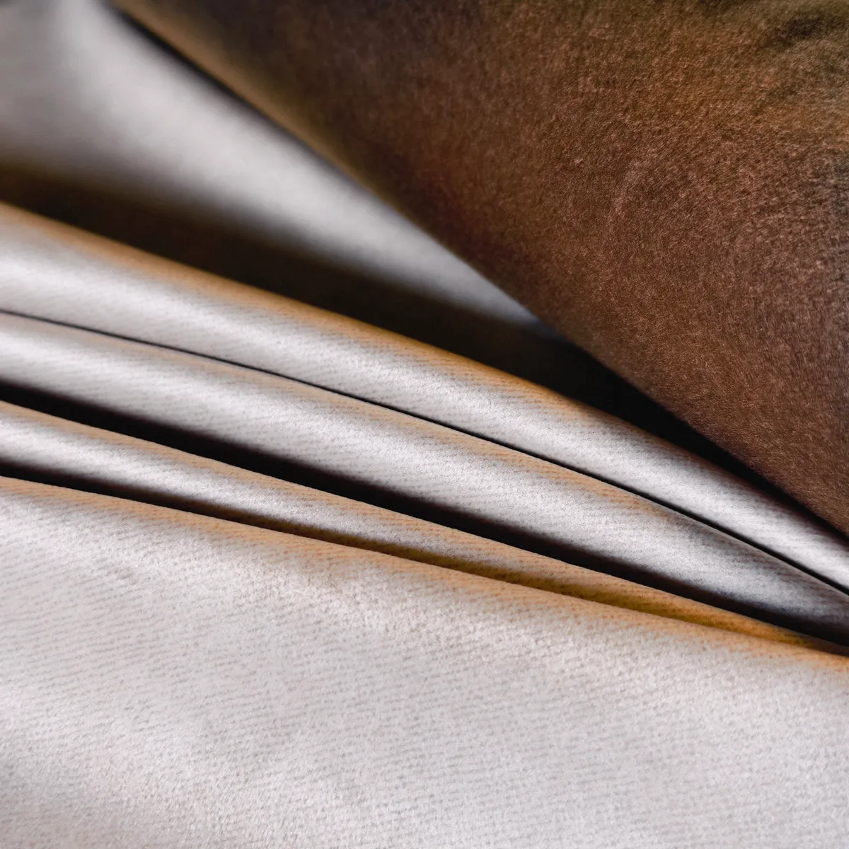 Gros plan sur deux textiles aux teintes beige clair et brun chaud mettant en avant la finesse de la surface et la douceur visuelle du tissu.